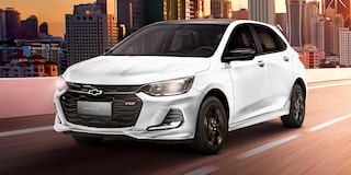 Onix RS circulando por autopista con edificios de fondo.