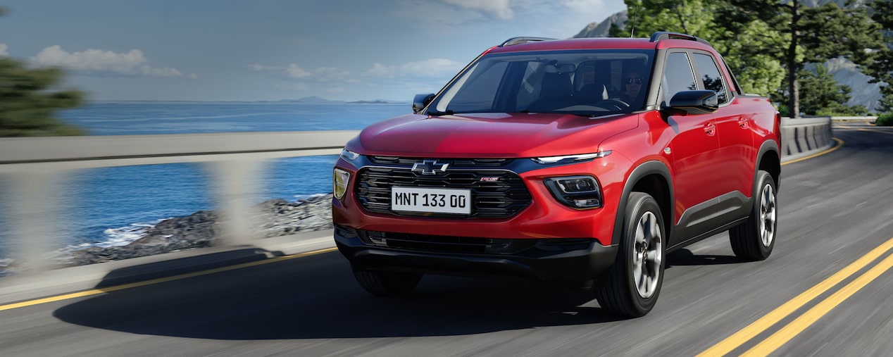 Chevrolet Montana circulando por una ruta con vegetación y océano de fondo.