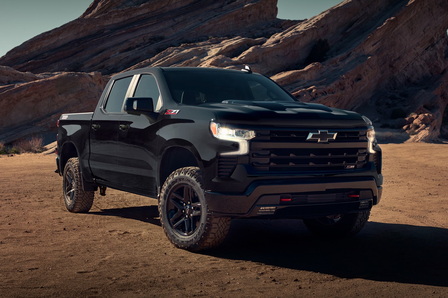 Chevrolet SIlverado color Negro estacionada en camino de tierra con formaciones rocosas de fondo.