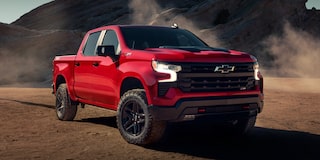  Chevrolet Silverado color Rojo Brillante estacionada en camino de tierra con formaciones rocosas de fondo.
