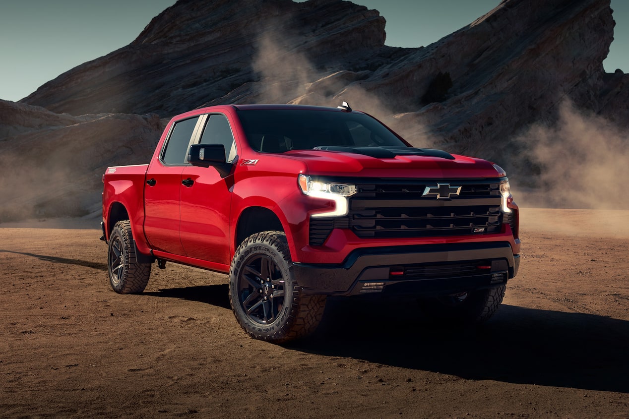 Chevrolet Silverado color Rojo Brillante estacionada en camino de tierra con formaciones rocosas de fondo.
