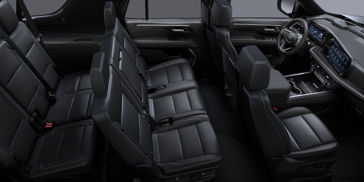 Interior de una Chevrolet Suburban Z71 con asientos delanteros tipo butaca y traseros tipo banca en EcoCuero negro, con insertos perforados, costuras y emblemas únicos.