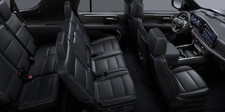 Interior de una Chevrolet Suburban Z71 con asientos delanteros tipo butaca y traseros tipo banca en EcoCuero negro, con insertos perforados, costuras y emblemas únicos.