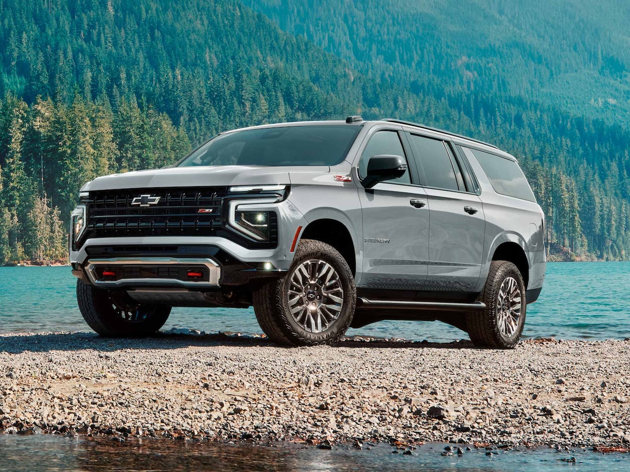 Chevrolet Suburban Z71 estacionada junto a un lago rodeado de montañas y bosques, en un entorno natural.