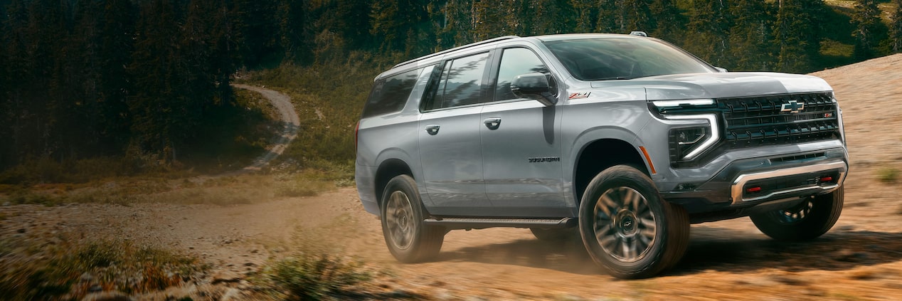 Chevrolet Suburban 2025 en color plata avanzando por un camino de tierra en la montaña.