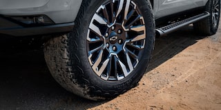 Detalle del rin y llanta todoterreno de la Chevrolet Tahoe 2025 Z71 sobre terreno de tierra
