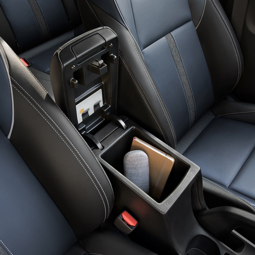 Vista en detalle del apoyabrazos con compartimiento con un cuaderno y un estuche de lentes dentro.