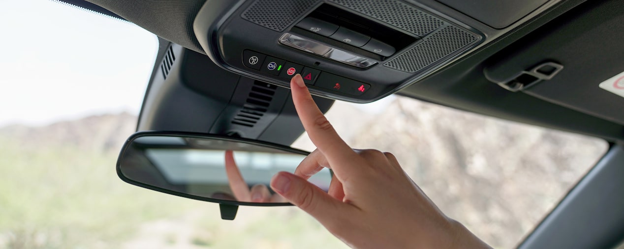 Persona presionando el botón OnStar de asistencia y emergencia en el interior de un vehículo Chevrolet