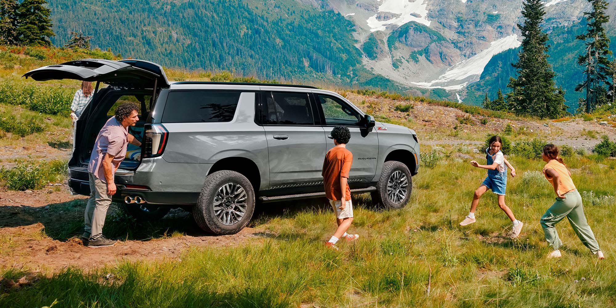 Familia disfrutando al aire libre junto a su Chevrolet Suburban Z71 en zona montañosa