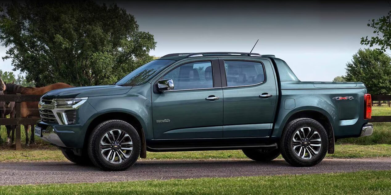Chevrolet Colorado High Country estacioanada en el campo, con caballos y árboles al fondo.