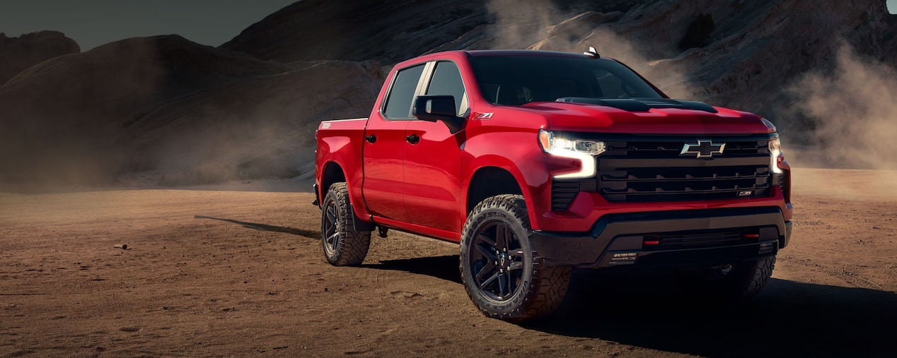 Chevrolet Silverado estacionada en camino de tierra con montañas de fondo.